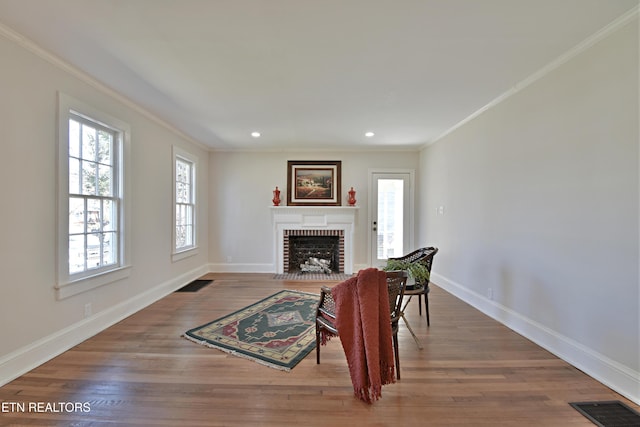 living area featuring a brick fireplace, visible vents, and wood finished floors