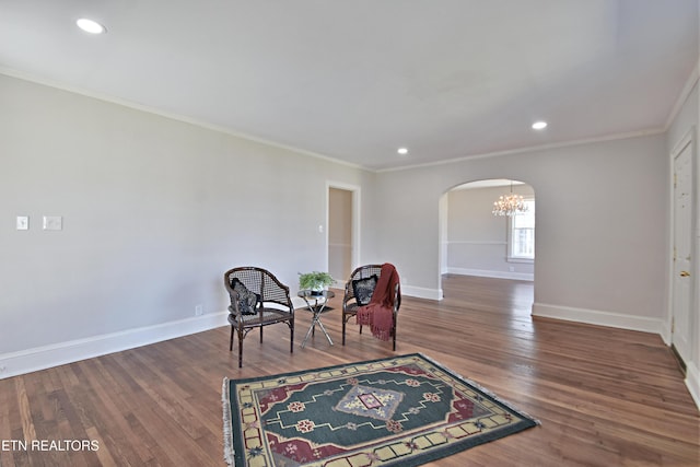 living area featuring arched walkways, crown molding, wood finished floors, and baseboards