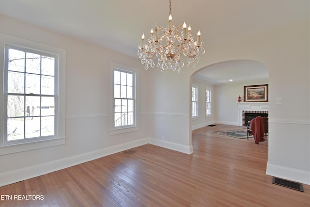 unfurnished dining area with light wood-type flooring, a wealth of natural light, a fireplace, and visible vents