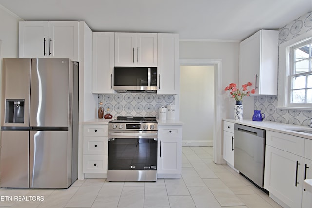 kitchen featuring crown molding, light countertops, decorative backsplash, appliances with stainless steel finishes, and white cabinets