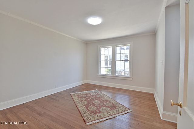 spare room with baseboards, crown molding, and wood finished floors