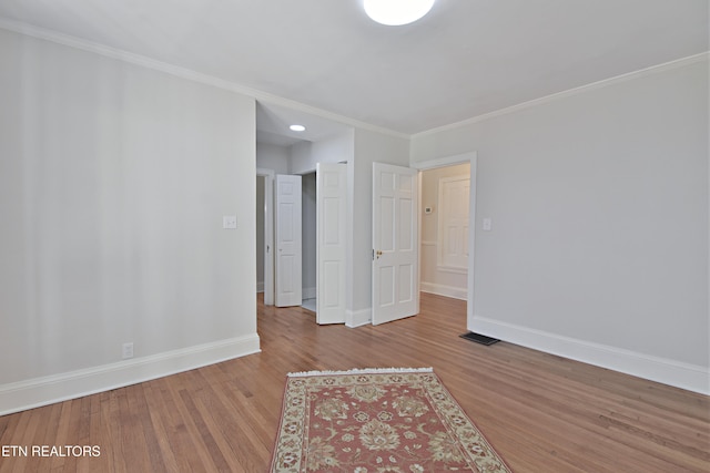 empty room with ornamental molding, baseboards, and wood finished floors