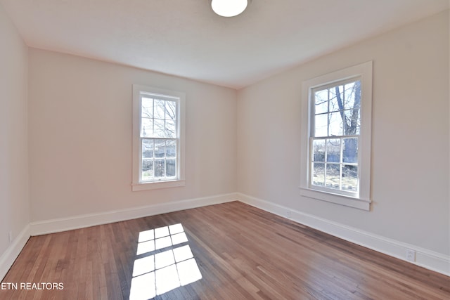 empty room featuring plenty of natural light, baseboards, and wood finished floors