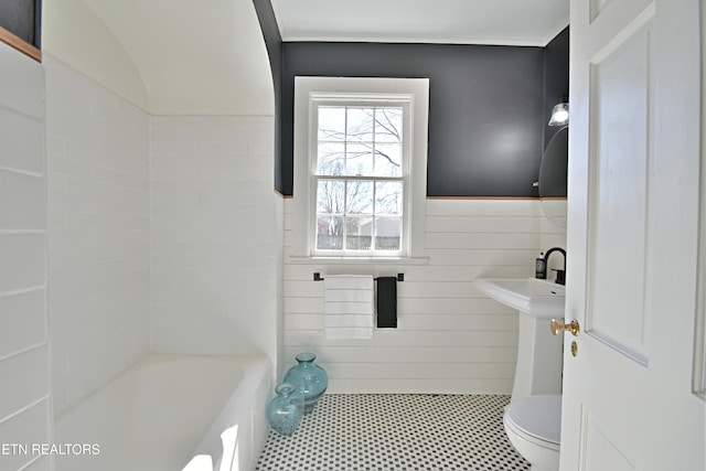 bathroom with toilet, a wainscoted wall, and tile walls