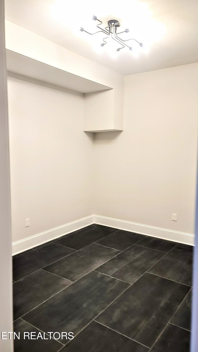 empty room with dark tile patterned floors and baseboards