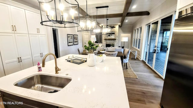 kitchen with high end refrigerator, white cabinets, open floor plan, a fireplace, and a sink