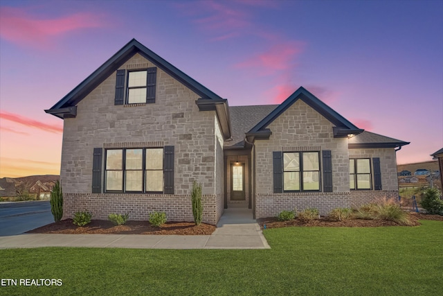 view of front of home with stone siding, a lawn, and brick siding