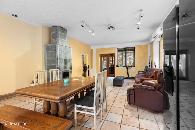 tiled dining area featuring ceiling fan, rail lighting, a wall mounted AC, and a textured ceiling