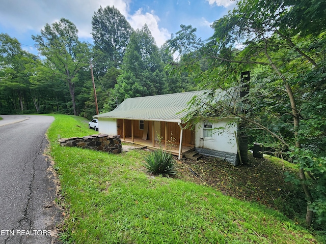 view of side of home featuring a yard and covered porch