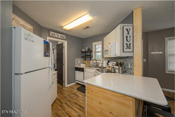 kitchen with a textured ceiling, white appliances, dark hardwood / wood-style flooring, white cabinets, and sink