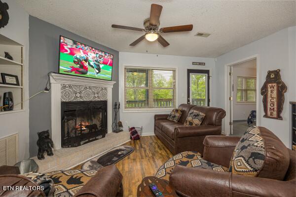 living room with a textured ceiling, wood-type flooring, and ceiling fan