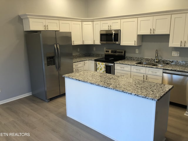 kitchen featuring sink, appliances with stainless steel finishes, stone countertops, white cabinets, and hardwood / wood-style flooring