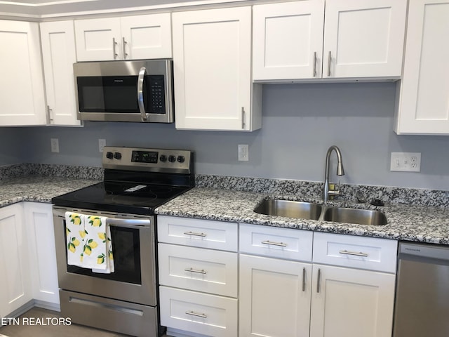 kitchen featuring light stone counters, sink, white cabinets, and stainless steel appliances