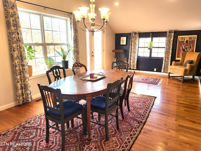 dining area with hardwood / wood-style floors, lofted ceiling, plenty of natural light, and a chandelier