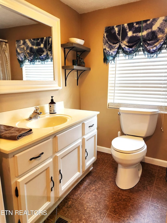 bathroom with tile floors, plenty of natural light, toilet, and large vanity