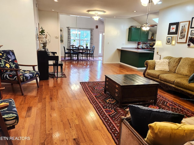 living room featuring lofted ceiling, ceiling fan, and light wood-type flooring