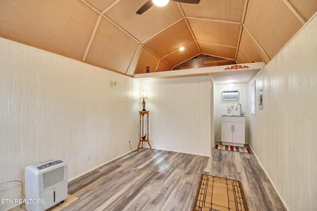 interior space with dark wood-type flooring, ceiling fan, sink, a wall unit AC, and vaulted ceiling