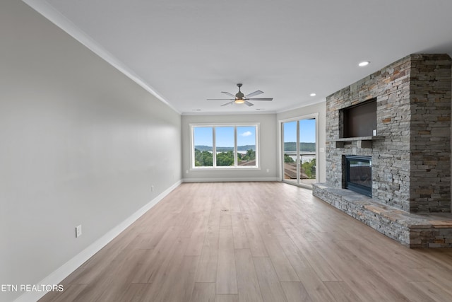 unfurnished living room with a stone fireplace, ornamental molding, and light hardwood / wood-style flooring