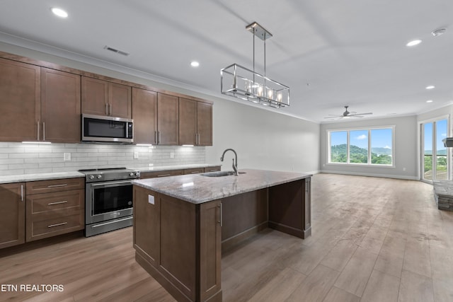 kitchen featuring stainless steel appliances, decorative light fixtures, light wood-type flooring, ceiling fan with notable chandelier, and sink