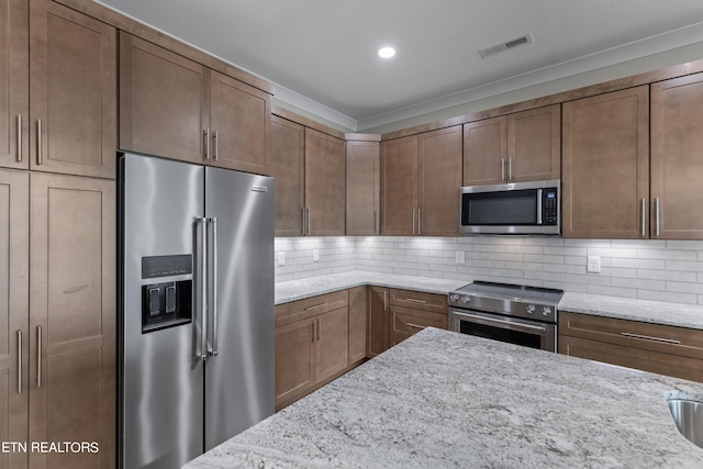 kitchen featuring high end appliances, light stone counters, and tasteful backsplash