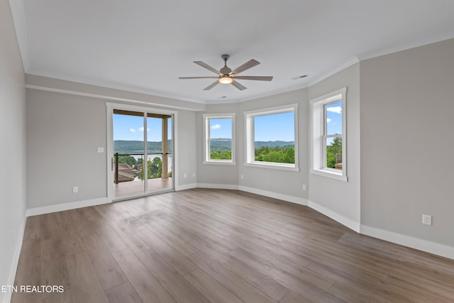 empty room with wood-type flooring, plenty of natural light, and ornamental molding