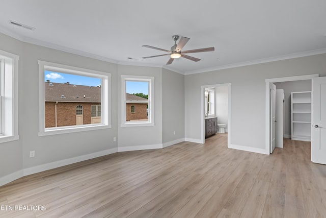 unfurnished bedroom featuring ceiling fan, light hardwood / wood-style flooring, crown molding, a spacious closet, and ensuite bath