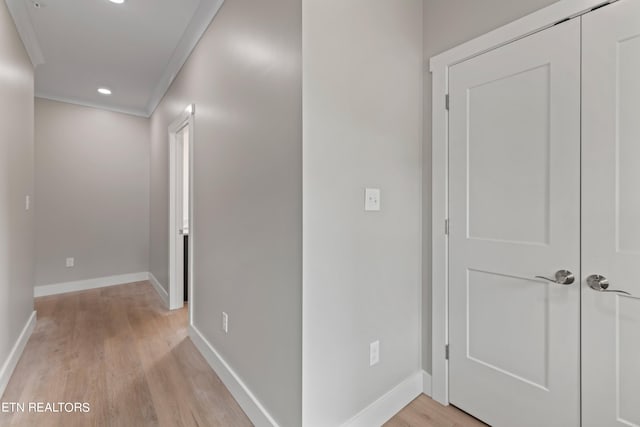 hallway with ornamental molding and light hardwood / wood-style flooring