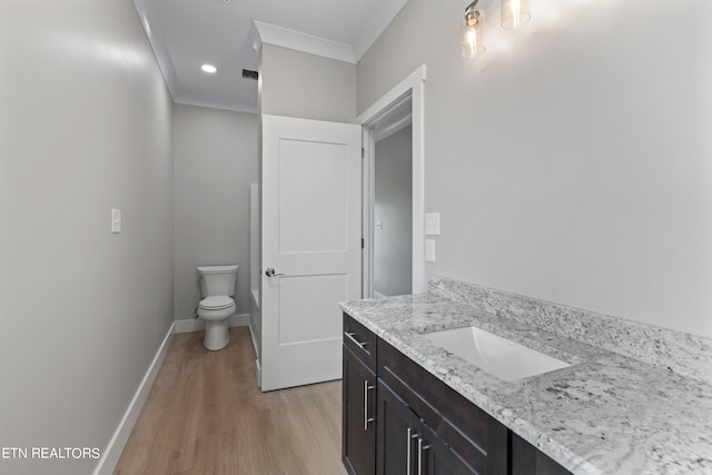 bathroom featuring toilet, vanity, hardwood / wood-style flooring, and ornamental molding