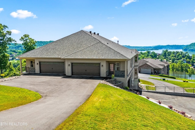 view of front of property featuring a front lawn, a garage, and a water view