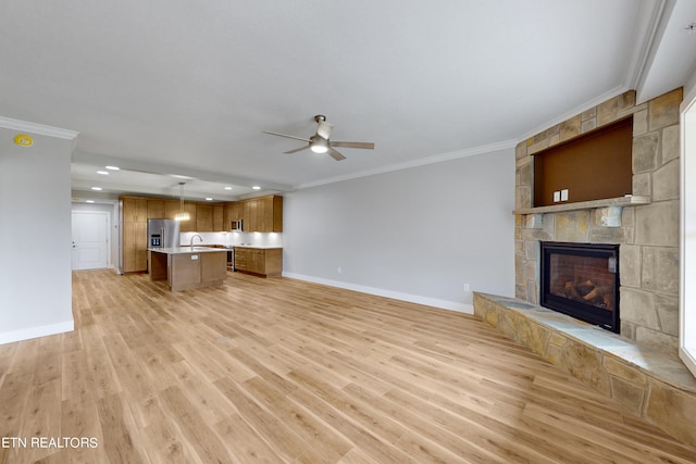 unfurnished living room with crown molding, a fireplace, and light wood-type flooring