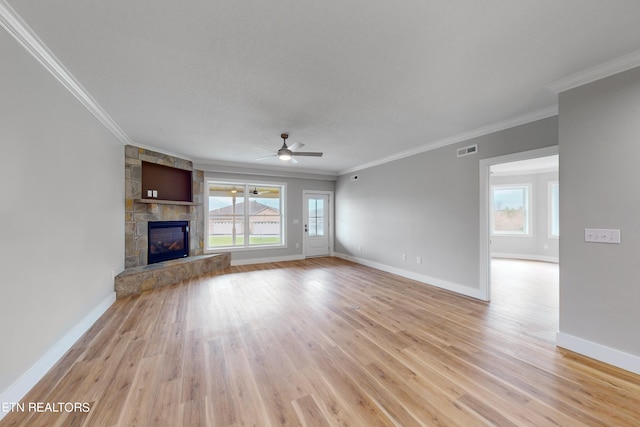 unfurnished living room with a stone fireplace, a healthy amount of sunlight, ornamental molding, and light hardwood / wood-style flooring