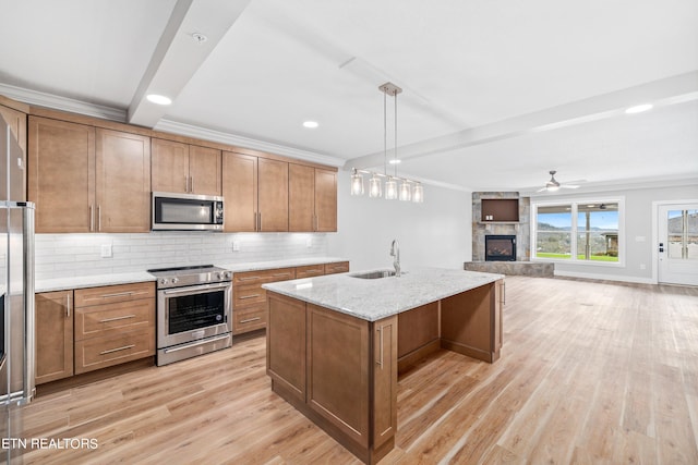 kitchen with hanging light fixtures, light hardwood / wood-style flooring, beamed ceiling, stainless steel appliances, and a stone fireplace