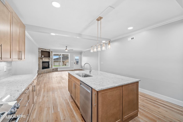 kitchen with sink, a fireplace, light wood-type flooring, and stainless steel dishwasher