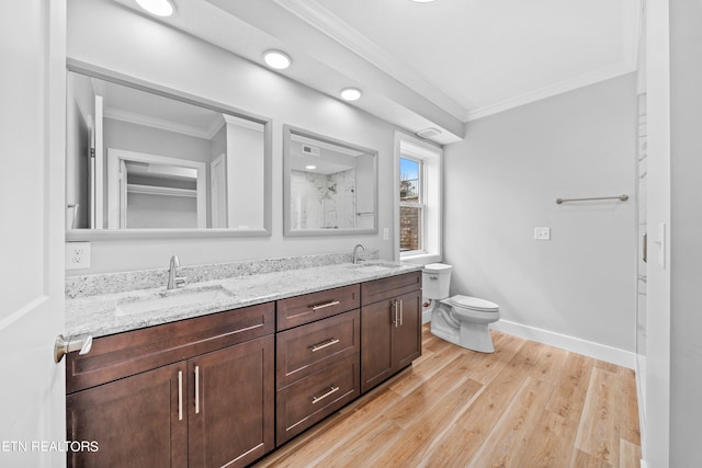 bathroom featuring double vanity, toilet, hardwood / wood-style floors, and crown molding