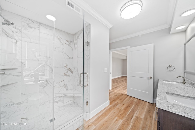 bathroom with wood-type flooring, dual vanity, ornamental molding, and a shower with door