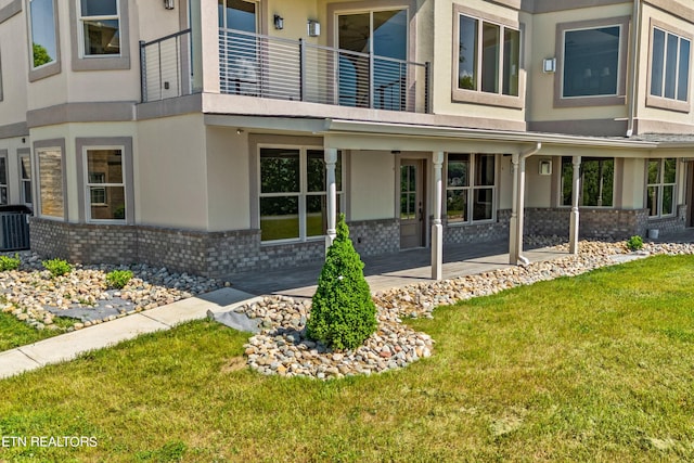 exterior space with a front yard, central air condition unit, and a balcony