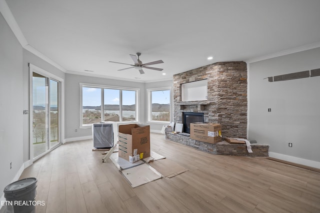 unfurnished living room with ceiling fan, a large fireplace, and light hardwood / wood-style flooring