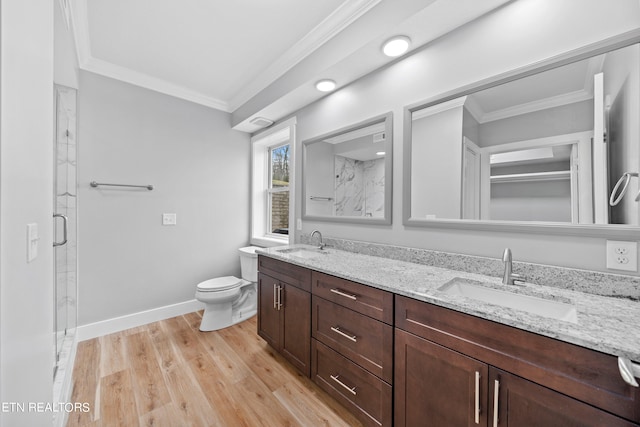 bathroom featuring ornamental molding, double sink, wood-type flooring, large vanity, and toilet