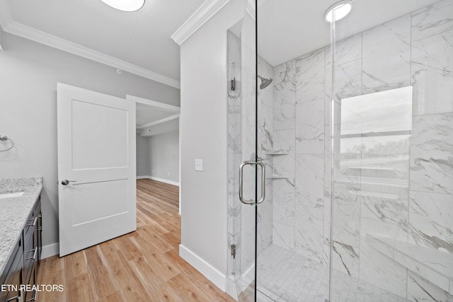 bathroom with a shower with door, ornamental molding, vanity, and wood-type flooring