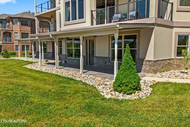 exterior space featuring a lawn, a balcony, and ceiling fan