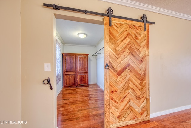 hallway with crown molding, a barn door, and light wood-type flooring