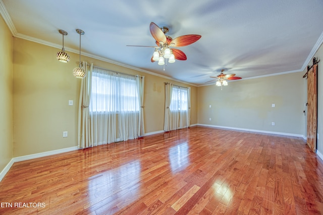 empty room with a barn door, crown molding, light hardwood / wood-style floors, and ceiling fan