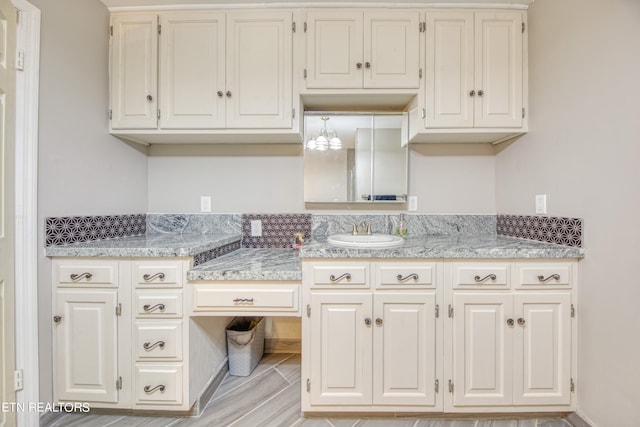 kitchen with white cabinets, light stone countertops, and sink