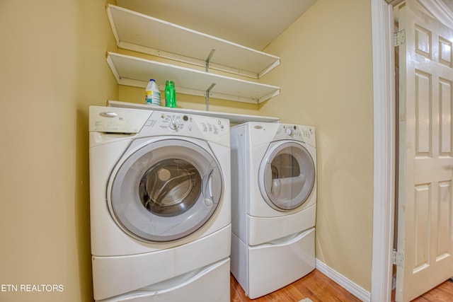 laundry room with separate washer and dryer and light hardwood / wood-style floors