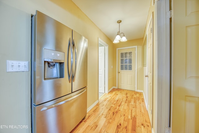 kitchen featuring stainless steel fridge with ice dispenser, light hardwood / wood-style floors, pendant lighting, and a chandelier