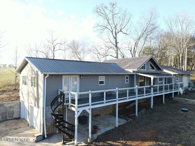 back of property with a wooden deck, a patio area, and a garage