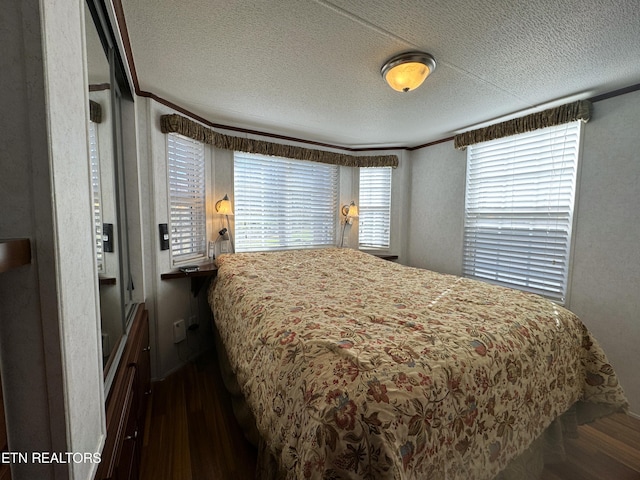 bedroom with a textured ceiling, dark hardwood / wood-style floors, and crown molding