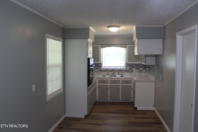 kitchen featuring black oven, dark wood-type flooring, crown molding, backsplash, and sink