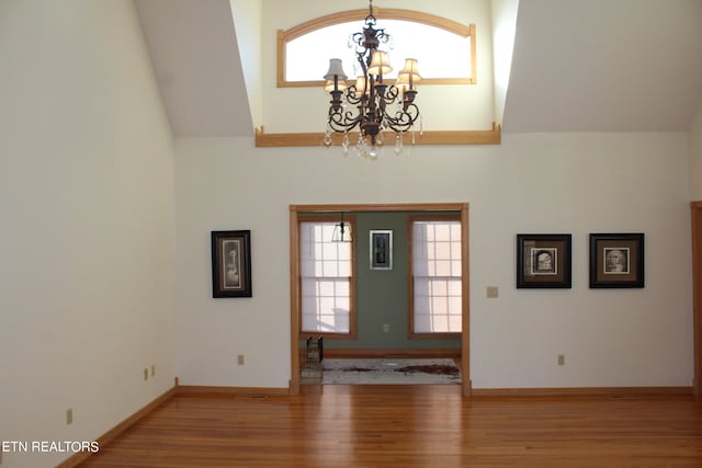 foyer featuring vaulted ceiling, hardwood / wood-style flooring, and an inviting chandelier