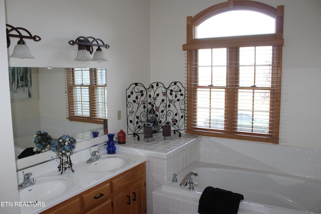 bathroom featuring a relaxing tiled bath, dual sinks, and vanity with extensive cabinet space